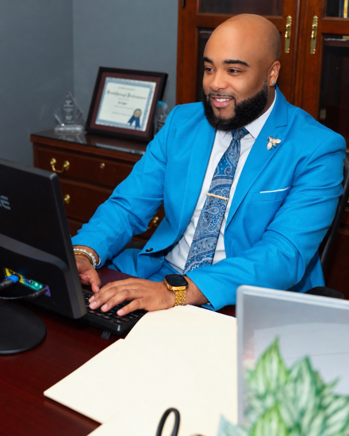 Brandon Anthony in a bright blue suit working at his computer